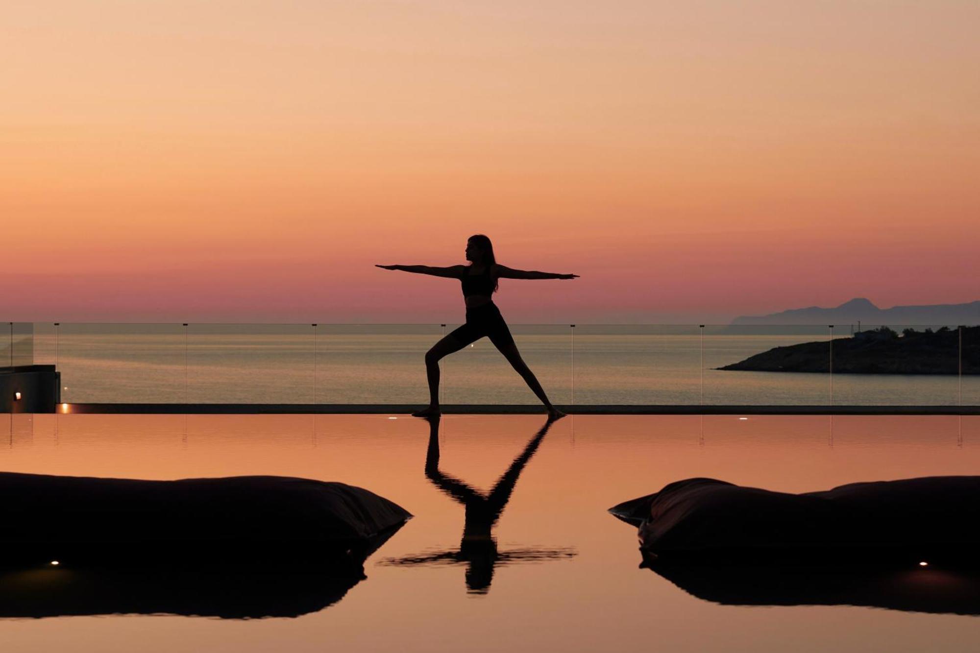 Minos Palace Resort - Adults Only آغيوس نيكولاوس المظهر الخارجي الصورة A woman practicing yoga at sunset